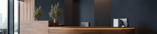 A modern office front desk with a desktop computer and plants.