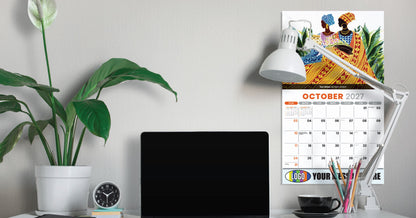 Desk setup with laptop, calendar, lamp, and plant on a light gray wall background
