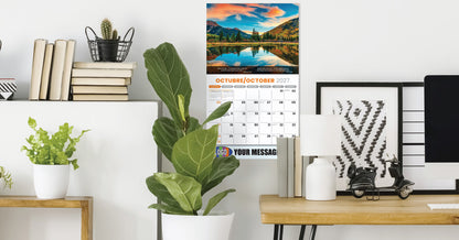 Modern office desk with plants, books, and a calendar on a white wall.